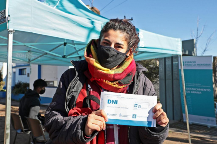 Mujer exhibe el sobre con su nuevo DNI frente al dispositivo de la Subsecretaría de Derechos Humanos y Renaper en Arana
