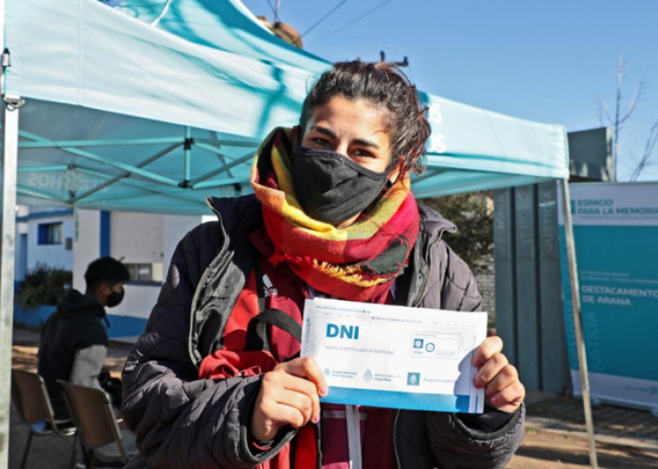Mujer exhibe el sobre con su nuevo DNI frente al dispositivo de la Subsecretaría de Derechos Humanos y Renaper en Arana